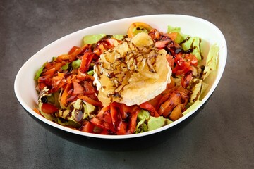 Close-up of a white bowl filled with a fresh goat cheese and pepper salad