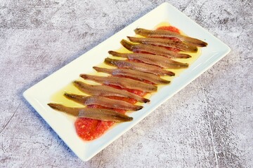 Close-up shot of a white plate containing a cooked fish in a brown sauce