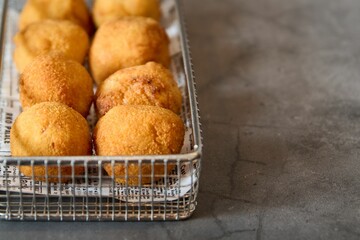 Metal basket filled with freshly-prepared, savory pastries coated in a crispy, golden-brown breading