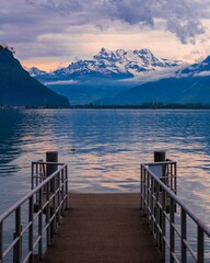 a dock with snow capped mountains in the background and a calm lake