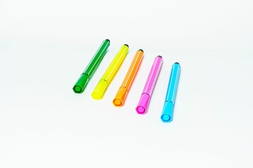 four bright colored pens lined up in a row on top of a table