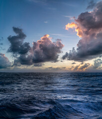 Beautiful view of ocean waves under cloudy sky at sunset