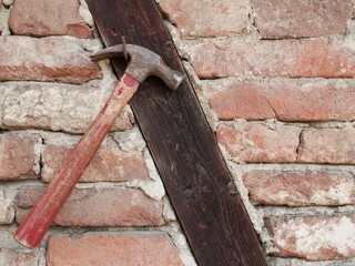 Closeup of a hammer hanging  from a nail on a stone wall under the natural light
