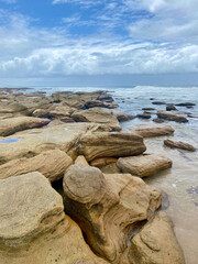 Vertical shot of rocky beach against cloudy sky