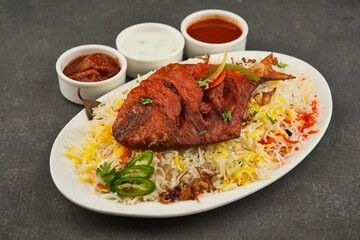 White platter filled with assortment of rice and grilled fish near sauces