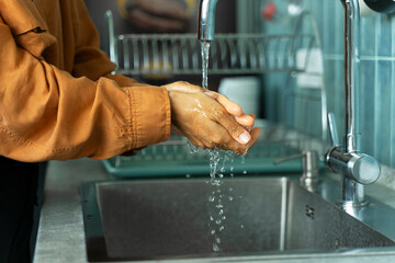 ?loseup of woman washing her hands before cooking at sink in kitchen. Hygiene concept