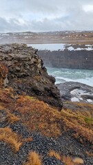 Fantastic Gullfoss waterfall in iceland with massive river flowing off mountain edge, northern wilderness nature. Icelandic scenery with snow covered fields and water stream running down cliffs.
