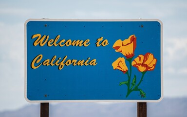 Welcome to California state sign in the foreground of a scenic highway, USA