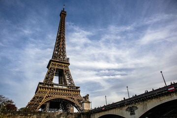 Low angle shot of the historical Eiffel Tower and a bridge over the Seine River in Paris, France