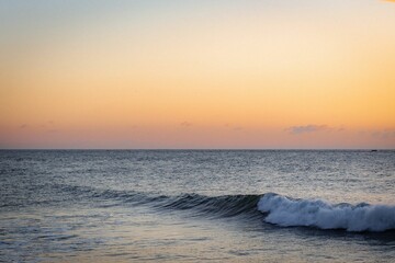 Captivating image of a calming sunset with a majestic ocean wave in the foreground