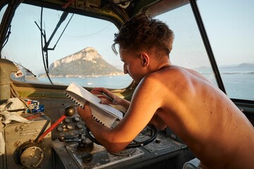 Caucasian male in the driver's cab of a locomotive taking notes