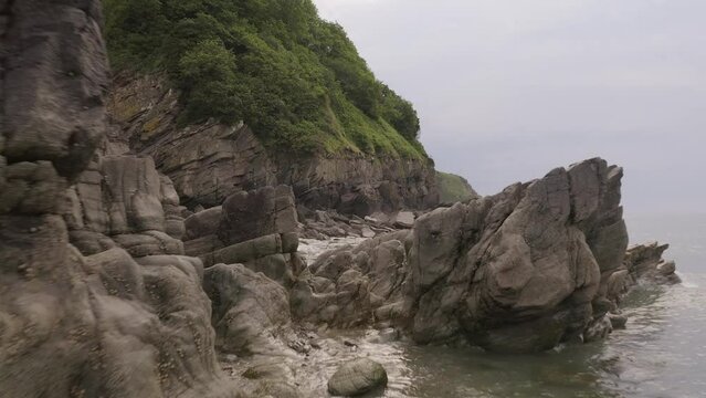 Aerial through rock pools to reveal the ocean, Devon, England