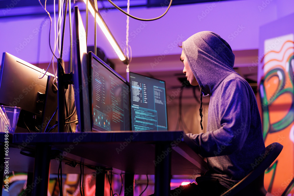 Poster internet criminal in hood planning online scam while coding malicious software on computer. asian ha