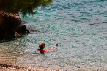 Młoda dziewczyna w stringach płynie na materacu po morzu. - obrazy, fototapety, plakaty