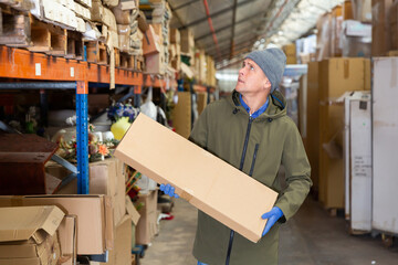 Warehouse worker carrying large box of goods in a warehouse