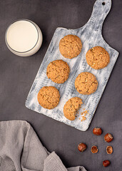 Food photography of oat biscuit; oatmeal; cookie;nut; hazelnut, milk, glass, pastry, dessert; wooden board