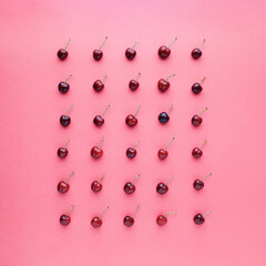 Square composition of cherries on pink table