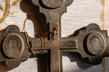 A small cross for the baptism of a child on the background of an old Holy large metal Cross.