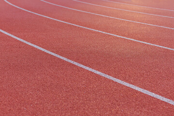 Close-up of the burgundy running track around the stadium illuminated by the morning light