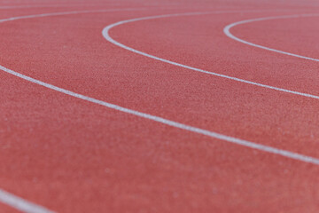 Fototapeta premium Close-up of the burgundy running track around the stadium illuminated by the morning light