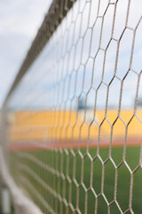 Close-up of soccer goal net in stadium against blue and yellow fan zone