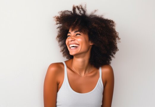 Young  woman smiling with afro hair standing against a wall