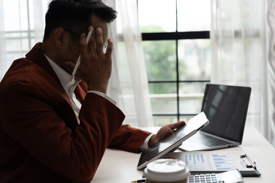 A businessman or professional person sitting stressed at work in an indoor workplaceat office job use computer laptop desk employee stressed problem corporate deadline