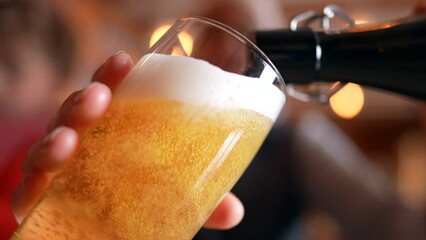 Filling Glass with Beer at Restaurant, traditional golden pour, close-up face holding refreshing drink
