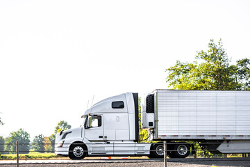 Professional industrial big rig white semi truck  tractor transporting cargo in reefer semi trailer...