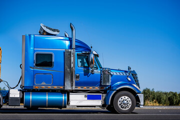 Stylish bright blue big rig bonnet semi truck tractor with extended cab and chrome roof spoiler...