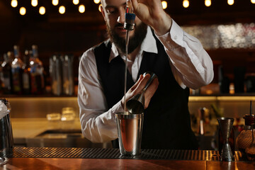 Bartender making fresh alcoholic cocktail at bar counter, selective focus