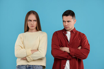 Portrait of resentful couple with crossed arms on light blue background - obrazy, fototapety, plakaty