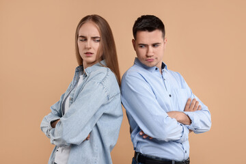 Portrait of resentful couple with crossed arms on beige background