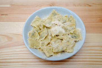 Top and close-up view at Ravioli on top with parmesan cheese, on the wooden table. 