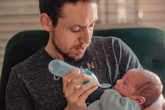 Father feeding his newborn baby with a silicone feeding bottle with spoon