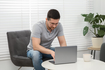 Man working with laptop at table in living room