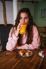 Beautiful young woman drinking orange juice glass during a brunch in a cafeteria