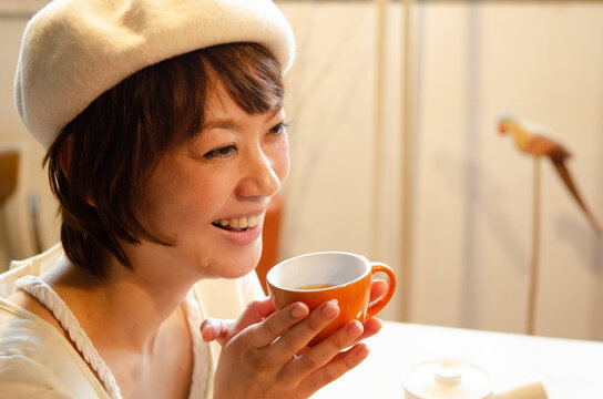 ベレー帽をかぶってお茶を飲んでいる女性