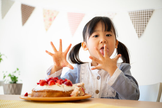 ケーキの前で指をなめている女の子