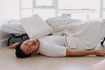 Asian man lying on floor snoring fall from white bed at home.