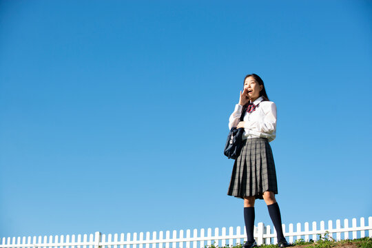口元に手を当てて叫んでいる制服姿の女子学生