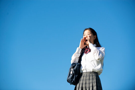 口元に手を当てて叫んでいる制服姿の女子学生