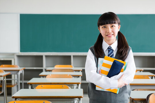 教室でノートを抱える女子中学生