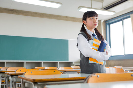 教室でノートを抱える女子中学生