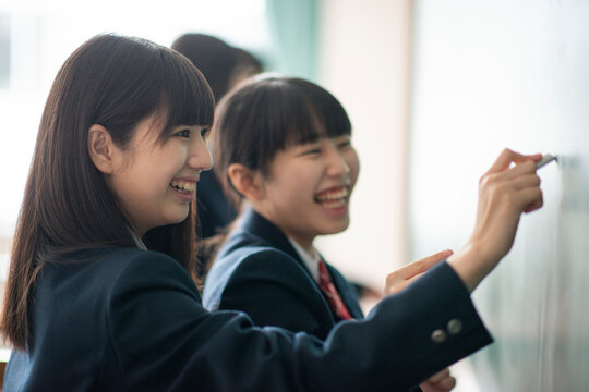 チョークで黒板に答えを書く女子学生