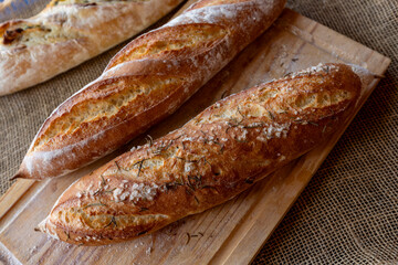 baguette with rosemary and coarse himalayan salt on a cutting board and  tablecloth