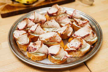 bruschetta with turkey meat and bazhe nut sauce, many servings on a tray, on a wooden table