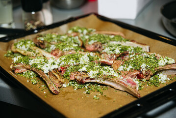 Lamb ribs with herbs, cheese and spices on a baking sheet. Meat preparation before cooking.
