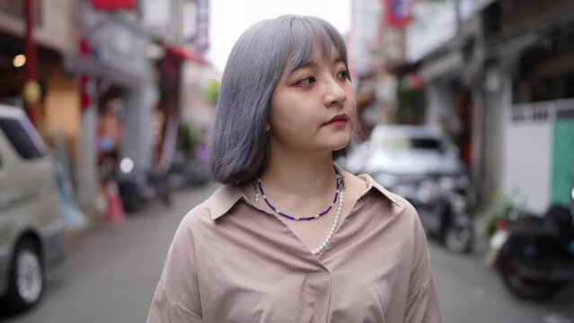 灰色の髪の若い台湾人女性が油化街の古い町並みを散策するスローモーション映像 Slow motion video of a young Taiwanese woman with gray hair strolling through the old streets of Dihua Street.