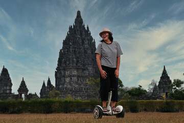 An Asian woman is riding a transporter, temples on the background